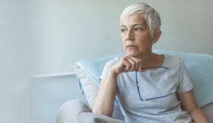 Woman in soft light holding her glasses and thinking about the question does medicare cover tms?