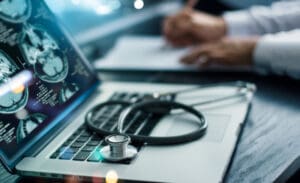 theta burst stimulation side effects represented by a stethoscope on a computer keyboard, witht he computer showing