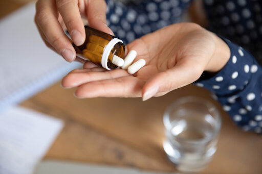 The question who takes antidepressants represented by hands pouring pills out of a bottle