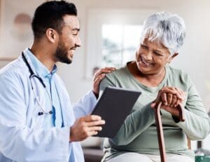 A young doctor sharing information about symptoms of Depression in older adults from his digital tablet with an older patient