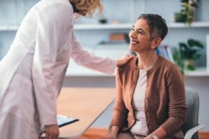 Patient sitting in a doctor's office smiling as the physician explains tms coil placement