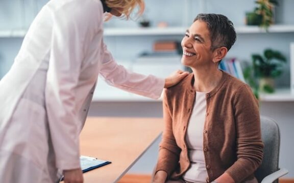 Patient sitting in a doctor's office smiling as the physician explains tms coil placement