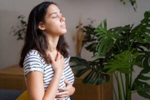 A person closing their eyes and smiling, with hands on their chest in comfort, after finding Depression relief with TMS
