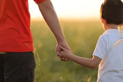 An adult holding a child's hand to represent the relationship between childhood trauma and Depression in adults